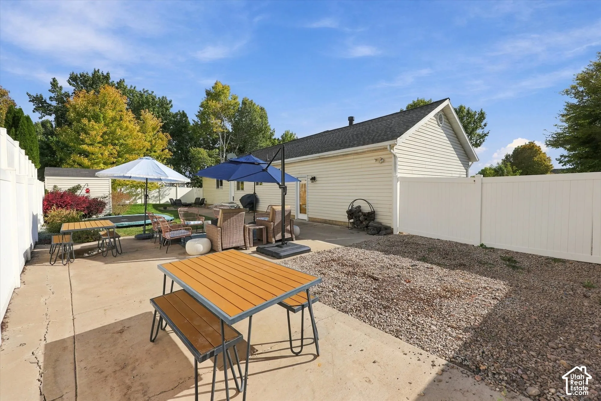 Expansive concrete patio with a white privacy fence and a gravel landscaping area
