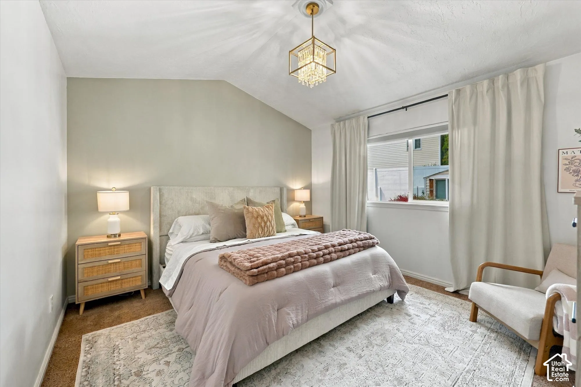 Vaulted ceiling with an ornate chandelier, window with privacy blinds, and neutral wall tones