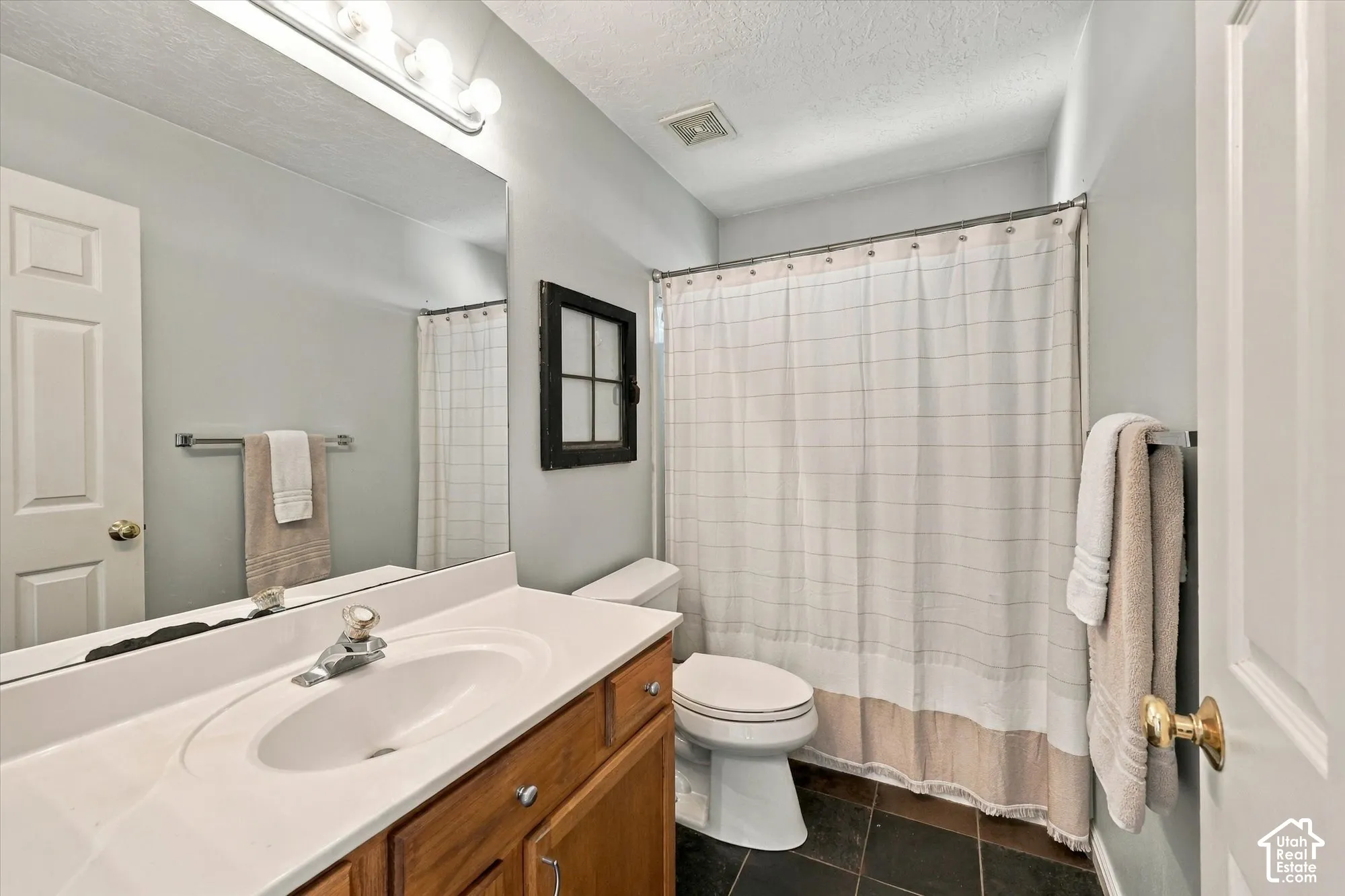 Bathroom featuring a vanity with an integrated sink, wood-finish cabinetry, a large mirror, and tile flooring