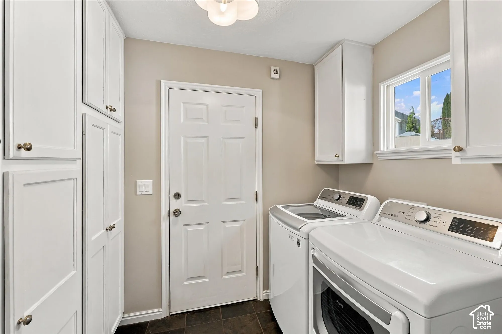 Ample built-in white cabinetry, paneled door, ceiling-mounted light fixture, and a window providing natural illumination