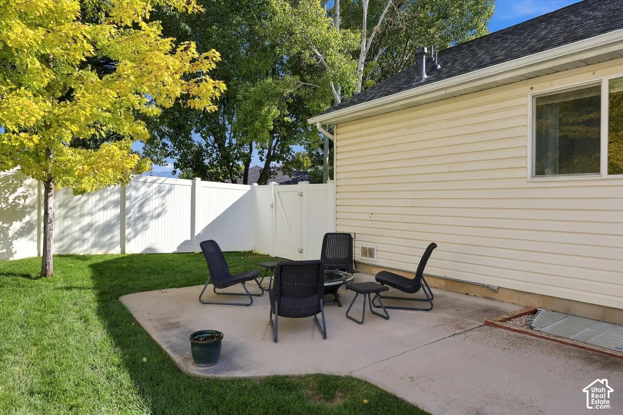 Manicured lawn, patio area, vinyl siding, white privacy fence with gate, and mature trees