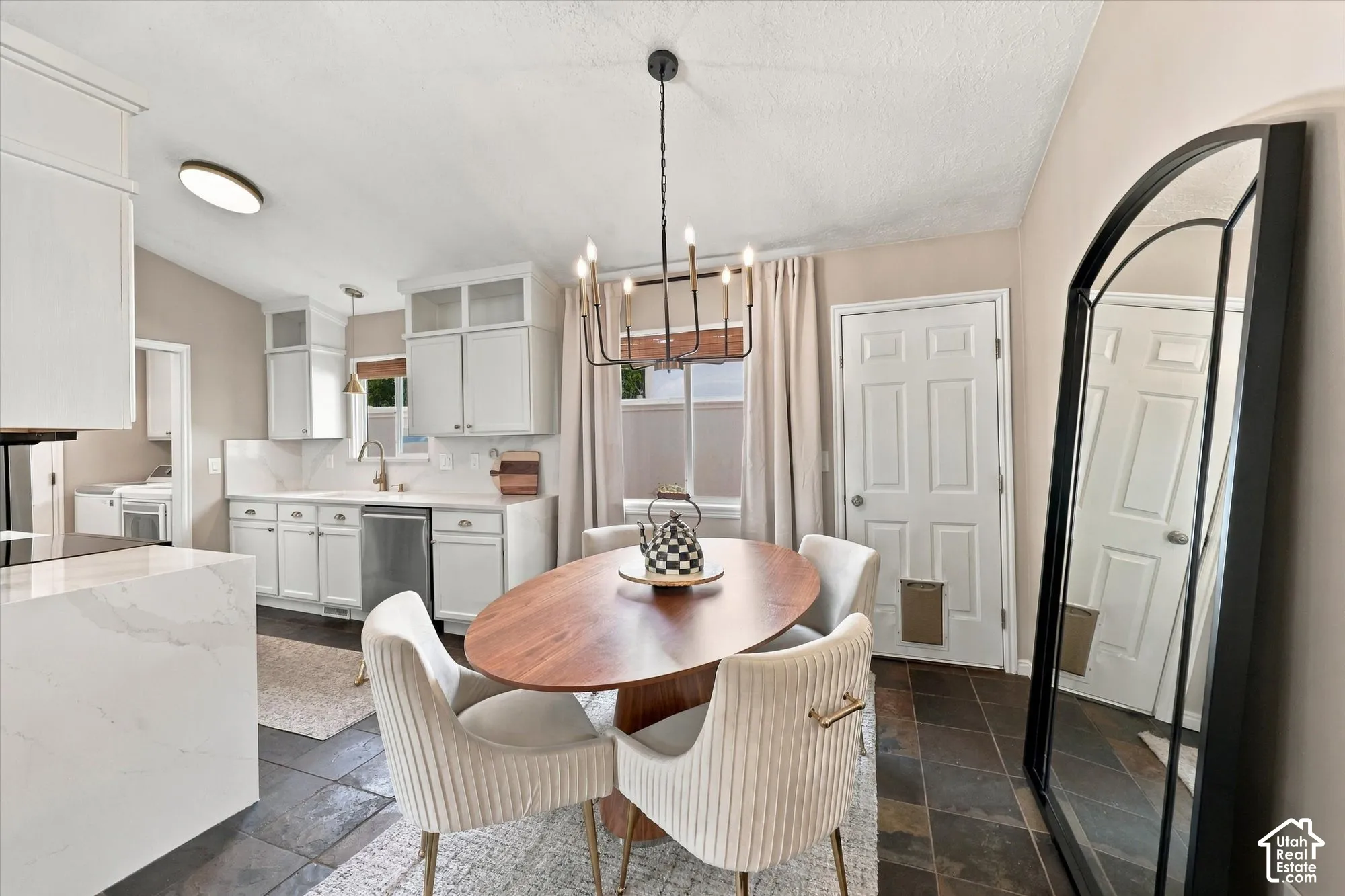 White cabinetry, pendant lighting, stainless steel dishwasher, white countertops, and dark floor tiling