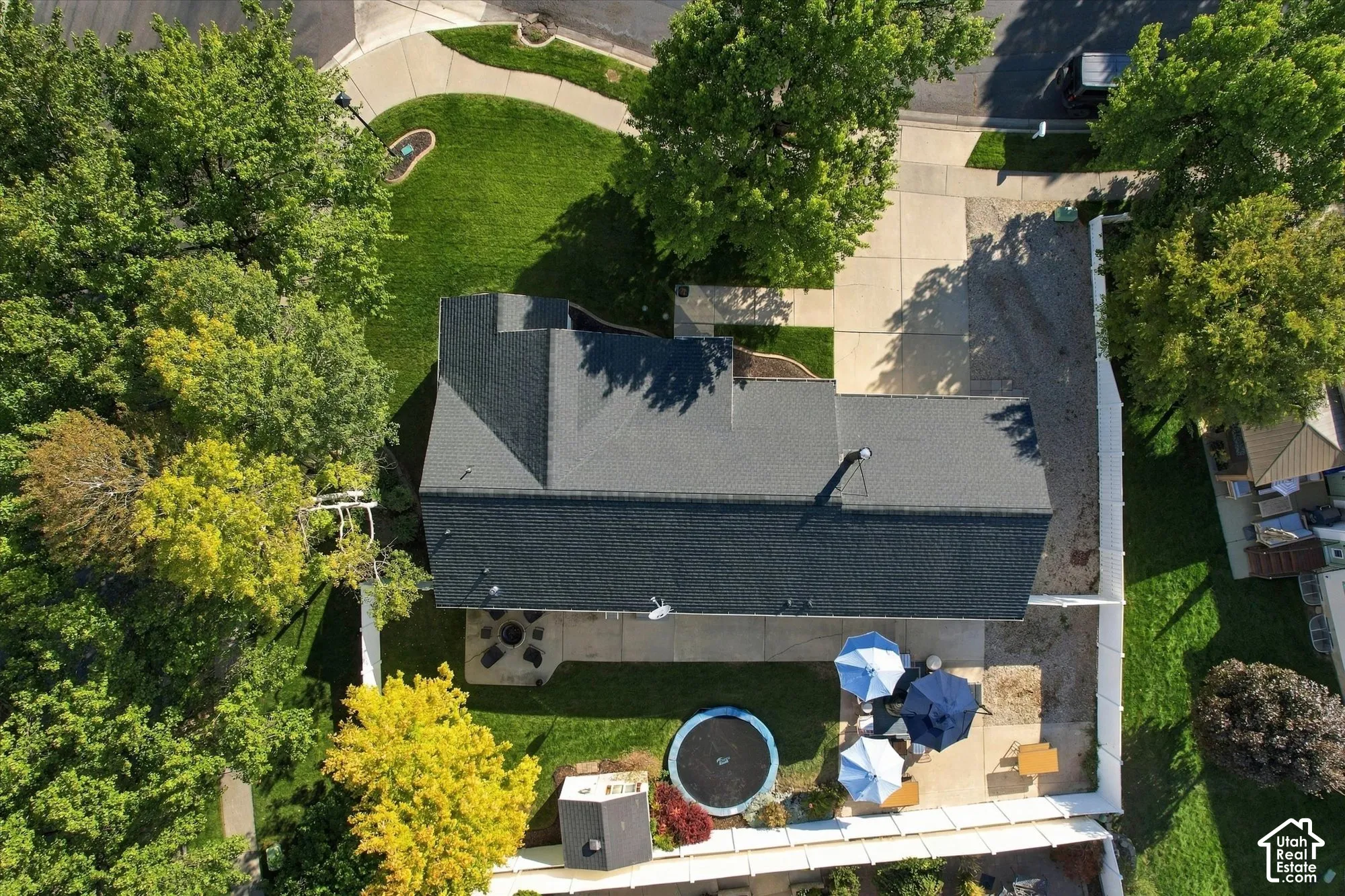 Asphalt shingle roof, expansive paved driveway, concrete patio, and fenced backyard