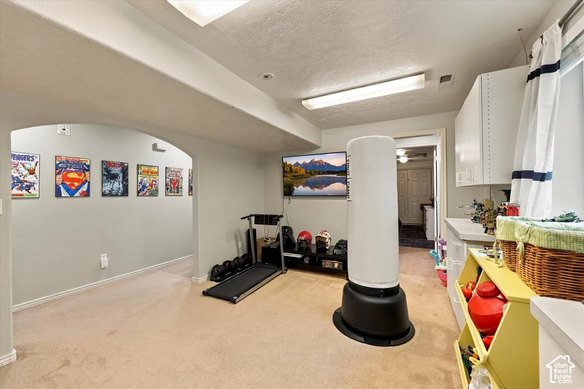 Arched doorway, recessed ceiling lighting, light-toned carpet flooring, white cabinetry, and a countertop surface