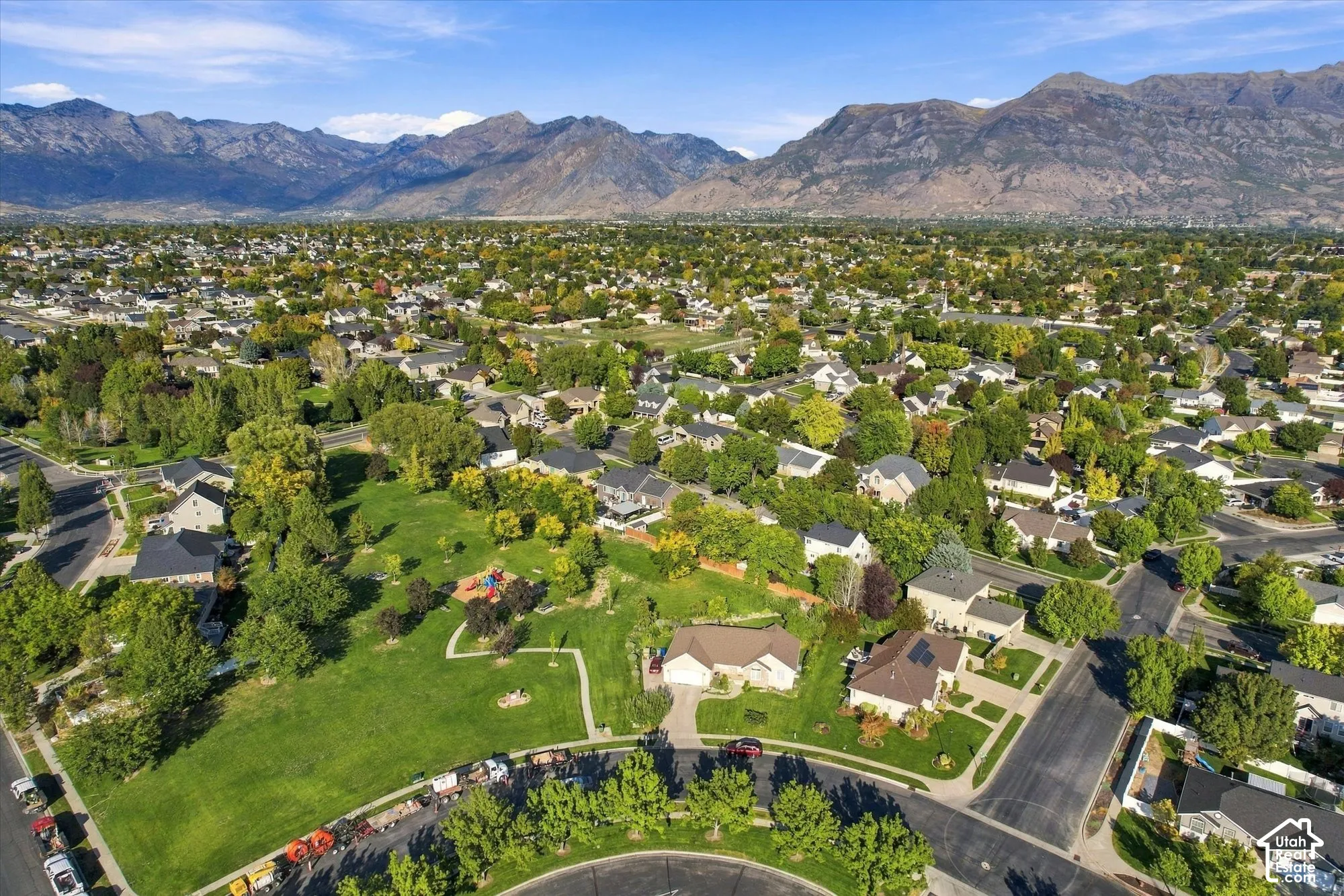 Residential community featuring mature trees, a park area with playground equipment, and mountain scenery
