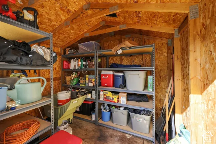 Interior storage shed with exposed wood paneling and rafters, featuring metal shelving units