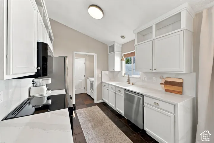Kitchen featuring white cabinetry, light-toned countertops, a stainless steel dishwasher, a built-in microwave, and dark-toned flooring
