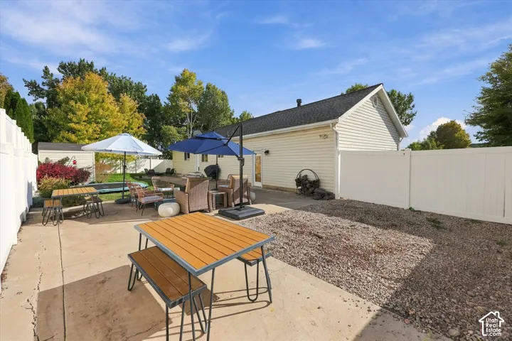 Expansive concrete patio with a white privacy fence and a gravel landscaping area