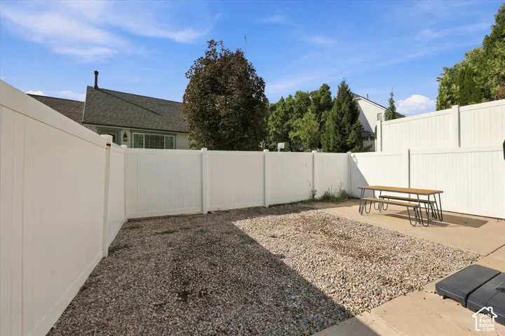 Enclosed yard featuring white panel fencing, a gravel area, and concrete paving