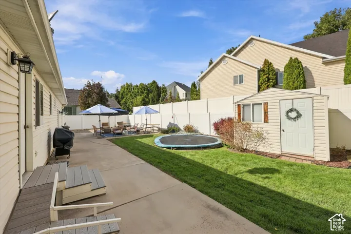 Expansive concrete patio with a separate lawn area, privacy fencing, and a dedicated storage shed