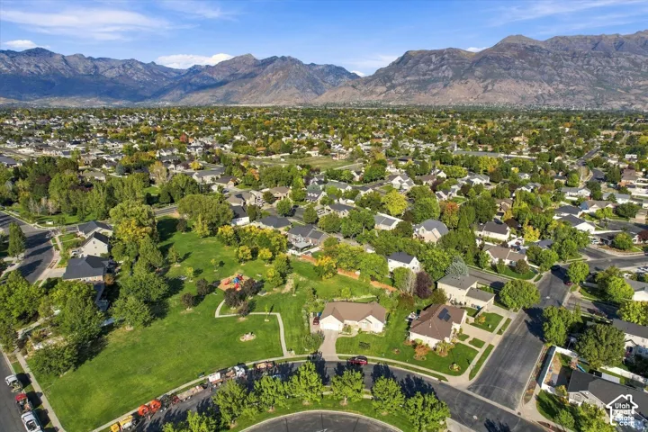 Residential community featuring mature trees, a park area with playground equipment, and mountain scenery
