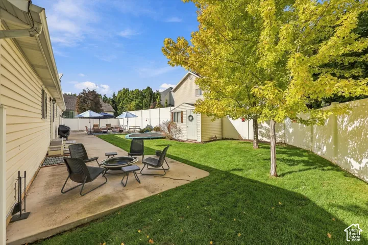 Expansive backyard with a concrete patio, green lawn, and privacy fencing