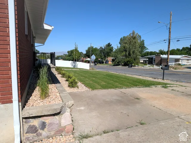 Brick exterior, paved driveway, landscaped rock garden, mature lawn, and street frontage