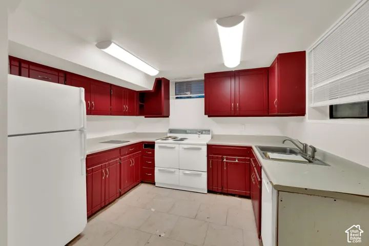 U-shaped kitchen with red cabinetry, white countertops, tile flooring, and integrated sink