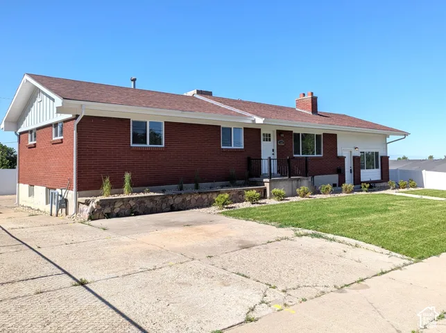 Brick ranch home featuring a spacious front facade with multiple windows, a pitched roof with asphalt shingles, and a concrete driveway