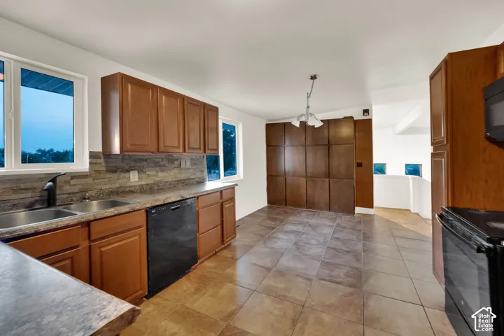 Kitchen featuring wood cabinetry, stone-finish backsplash, dual basin sink with matte black faucet, and tile flooring