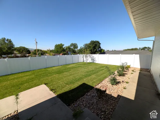 Expansive backyard featuring a manicured lawn, full-height privacy fencing, and a gravel landscape bed with plantings