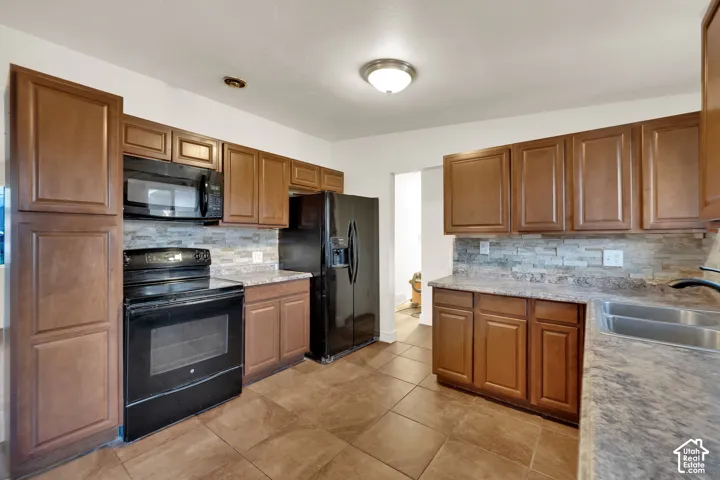 Kitchen featuring wood cabinetry, stone-look countertops, and a tile backsplash