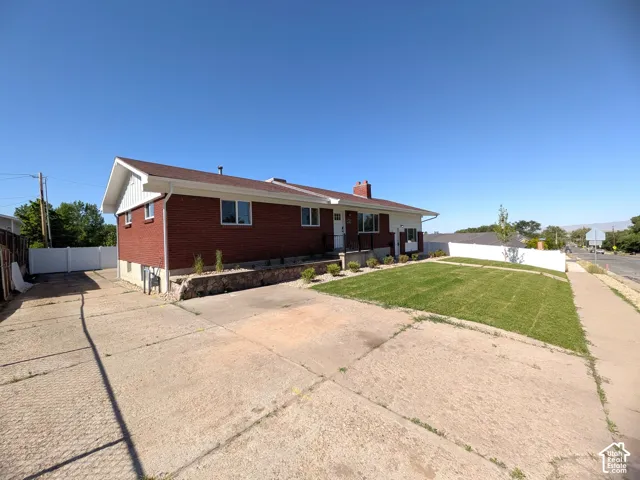 Brick exterior with white trim, well-maintained lawn, privacy fencing, and a concrete driveway
