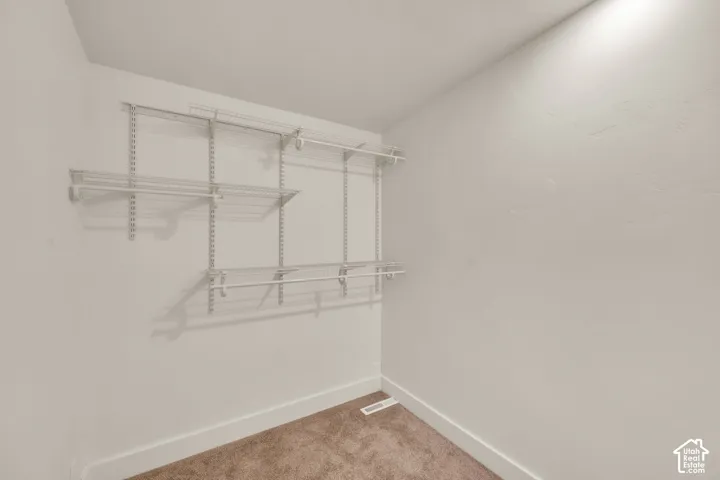 Closet with wire shelving system and hanging rods, complemented by brown carpet flooring
