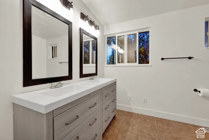 Dual vanity with white countertop, chrome fixtures, and a light wood-finish cabinet
