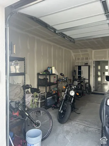 Attached garage with concrete flooring, unfinished drywall, and exposed ceiling framing