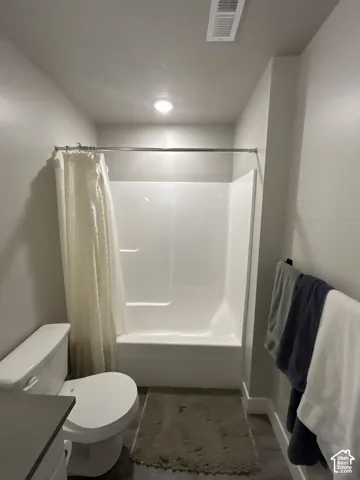 Clean white tub and shower combination with a full wall surround, recessed lighting, and wood-finish flooring