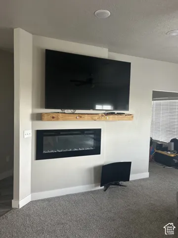 Built-in electric fireplace with a wood-finish mantel and recessed ceiling lighting