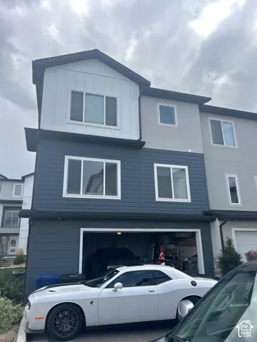Three-story exterior featuring a two-car garage, multiple windows, and a mix of horizontal and vertical siding
