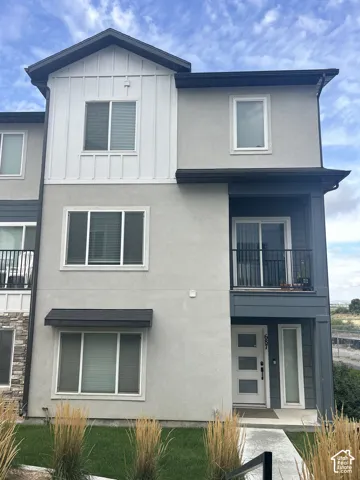 Multi-level exterior featuring vertical siding, stucco finish, and a black railing balcony