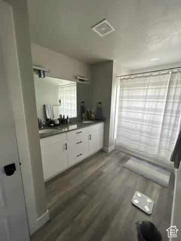 Dual vanity with undermount sinks, gray countertop, and white cabinetry featuring black hardware