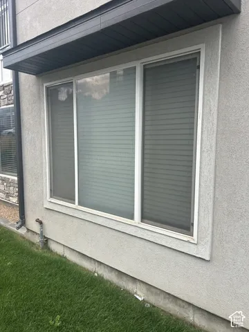 Three-panel window set with white frames, complemented by a dark overhang and a stucco exterior finish