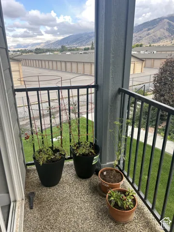 Balcony access with a black metal railing, textured flooring, and mountain scenery
