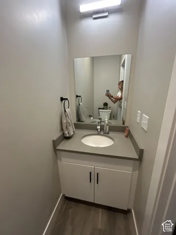 Vanity with a built-in sink, gray countertop, and white cabinetry featuring black hardware