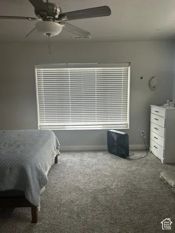 Recessed window with horizontal blinds, overhead ceiling fan with light fixture, and plush carpeting throughout