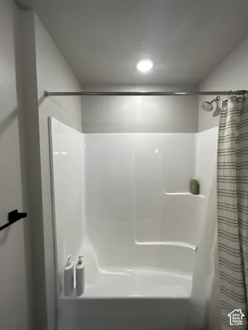White shower-tub combination featuring an integrated shelf and a chrome shower head
