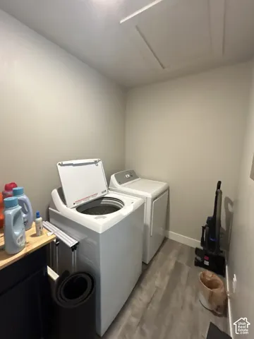 Laundry area featuring wood-finish flooring, light neutral walls, and a ceiling-mounted access panel