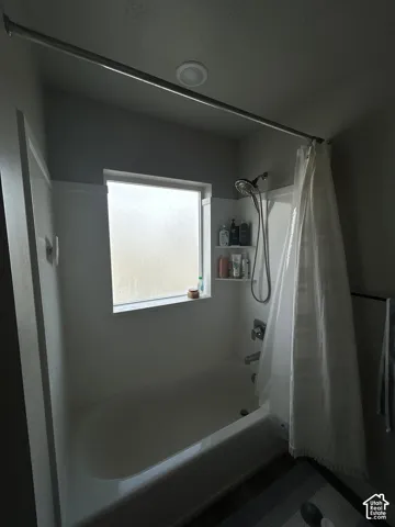 Tub-shower combination with a frosted window, mounted shower caddy, and overhead recessed lighting
