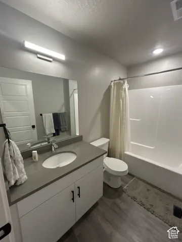 Vanity with grey countertop, white cabinetry with black hardware, undermount sink, and chrome faucet