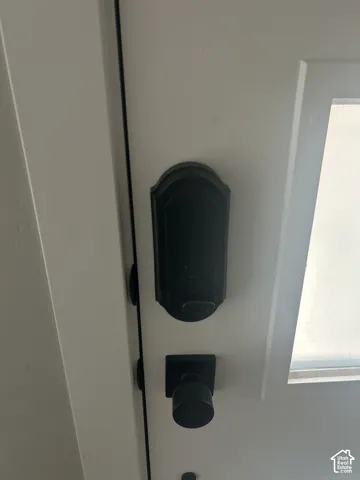 White door with dark hardware, featuring a black smart lock and a black doorknob