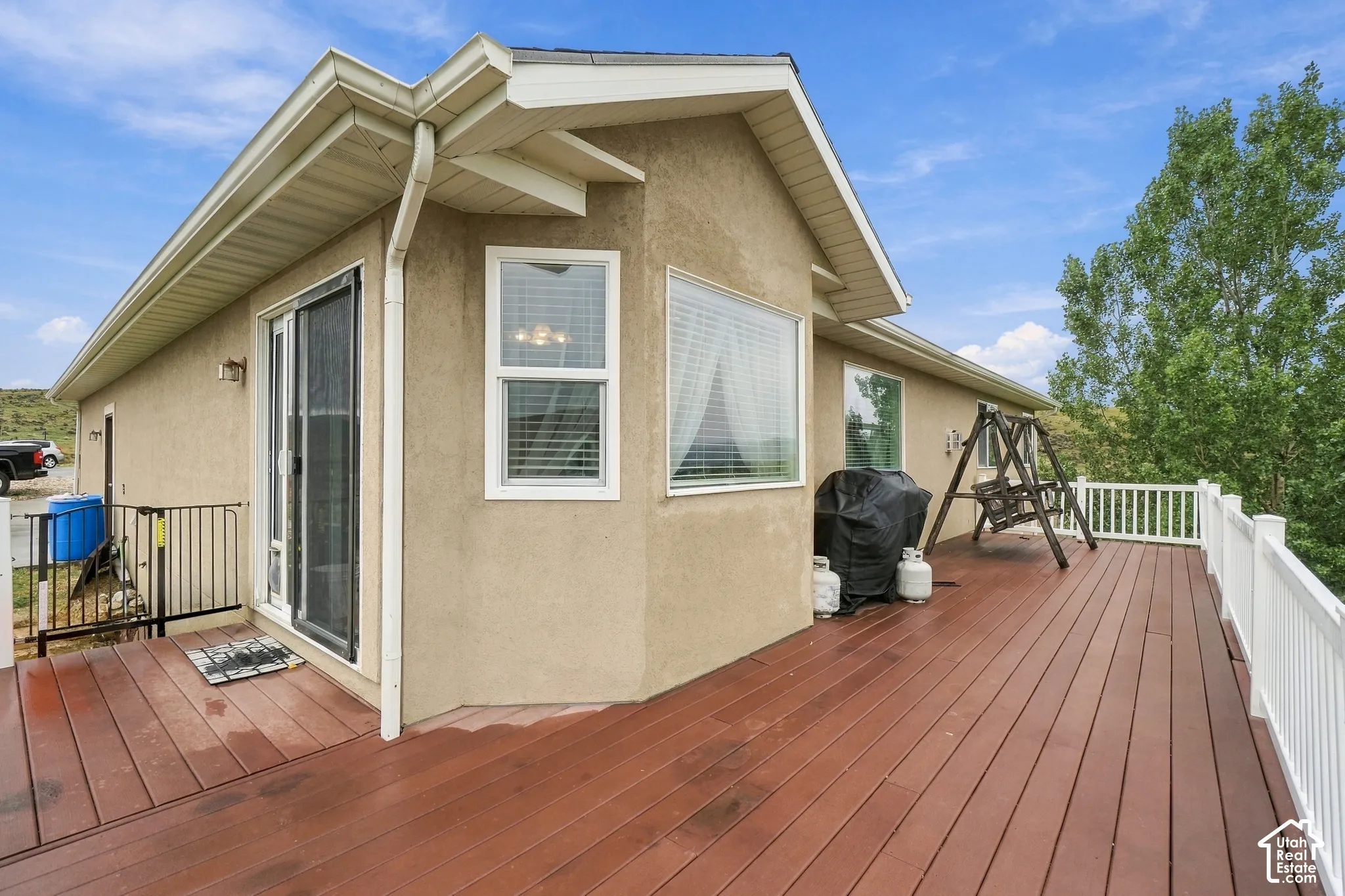 Expansive outdoor deck with wood-finish flooring, white railing, and stucco exterior