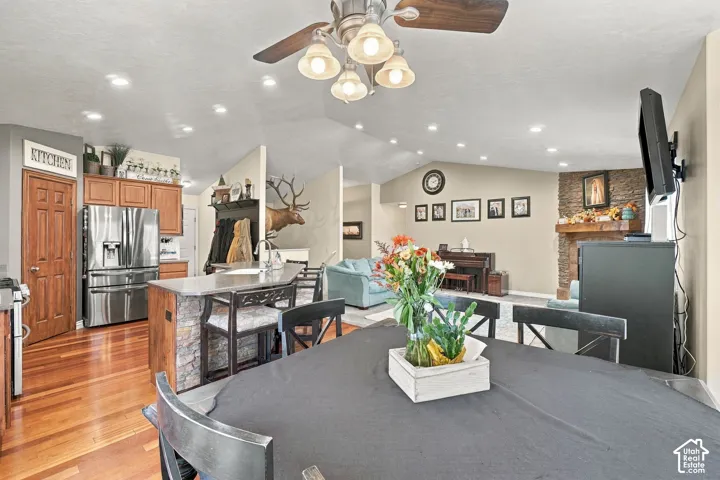 Open-concept living area featuring a kitchen with wood cabinetry and stainless steel appliances, a stone-clad island, and a living room with a stone fireplace