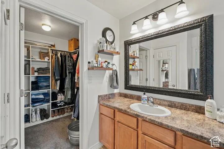 Vanity with a single basin sink, laminate countertop, and wood-finish cabinetry