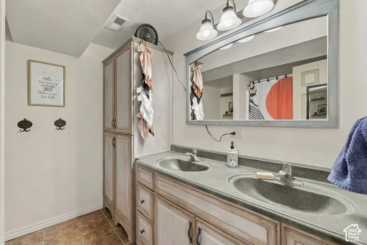 Dual basin vanity with integrated sinks and individual faucets, complemented by a large framed mirror with overhead lighting