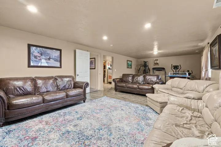 Recessed lighting illuminates the expansive room with wood-finish flooring