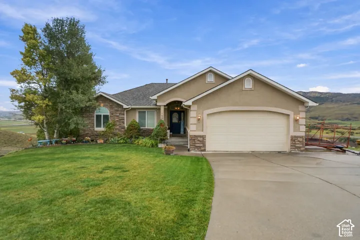 Stucco and stone facade with arched entry, two-car garage, and a concrete driveway