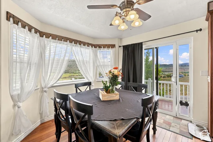 Dining area with wood-finish flooring, a ceiling fan with light fixture, and a bay window