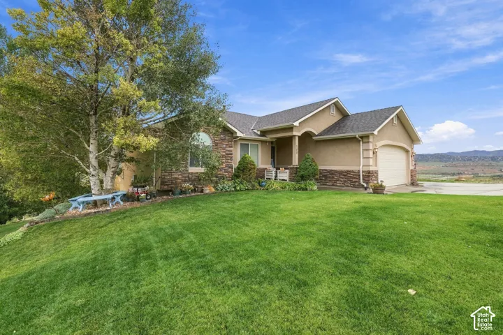 Stucco exterior with stone accent, arched entry, arched window, attached garage, and a lush lawn