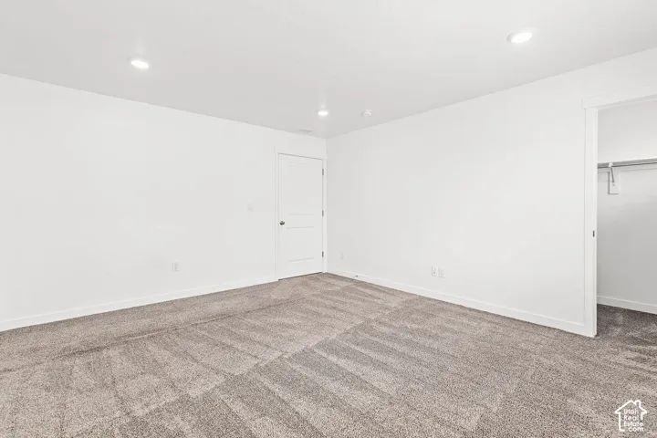 Neutral wall finishes, recessed lighting, and soft pile carpeting