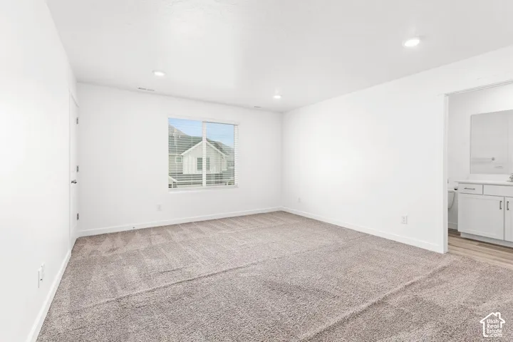 Recessed lighting, neutral-toned carpeting, ample natural light, and a dedicated bathroom access point